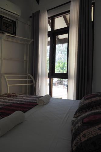 a bedroom with a bed with a large window at Mahaon surf hotel in Weligama
