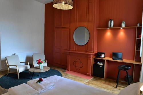 une chambre avec un lit, une table et un miroir dans l'établissement Les Chambres du Cloître, la Pâtissière, à Limoges