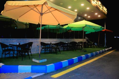 a group of tables with umbrellas on the grass at Delmar Hotel Matrouh in Marsa Matruh