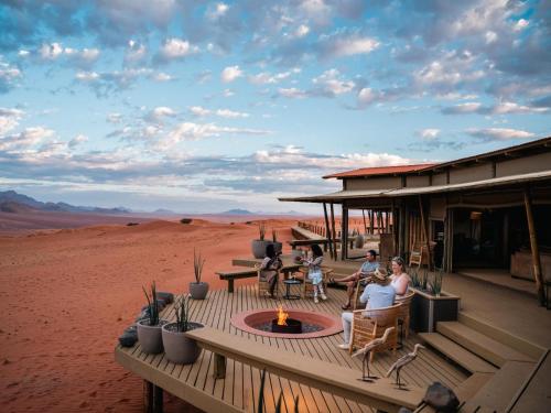 Un grupo de personas sentadas en un porche en el desierto en Wolwedans Desert lodge, en NamibRand