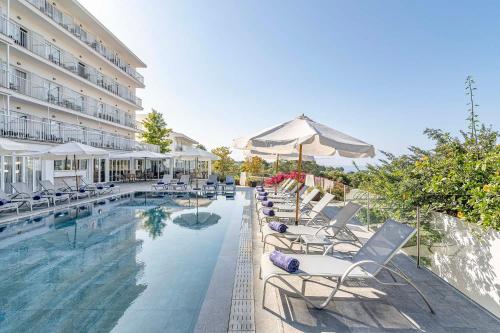a hotel swimming pool with chairs and an umbrella at Exe Portals Nous in Portals Nous
