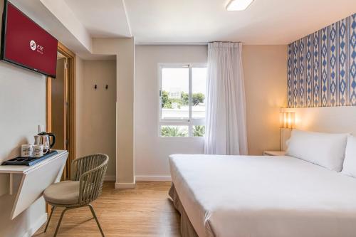 a hotel room with a bed and a desk and a window at Exe Portals Nous in Portals Nous