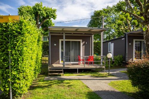 a tiny house with a porch and red chairs at Camping Rose in Dormelletto