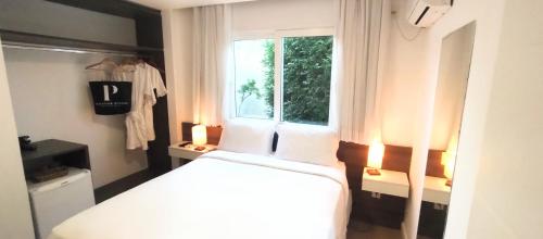a bedroom with a white bed and a window at Parador Búzios Boutique Hotel in Búzios