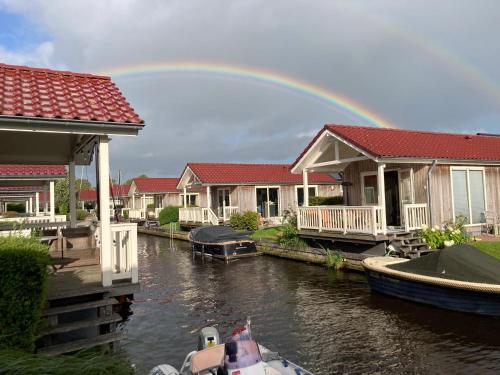 a rainbow over a group of houses on a river at Recreatiepark Tusken de Marren in Akkrum