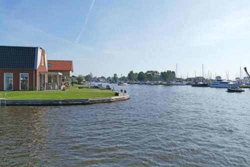 a building on the side of a river with boats at Recreatiepark Tusken de Marren in Akkrum