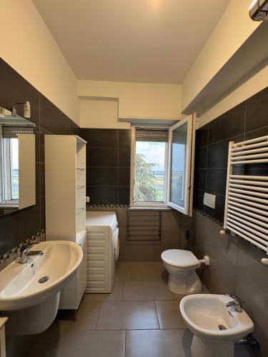 a bathroom with two sinks and a toilet and a window at Fly & chill in Ciampino