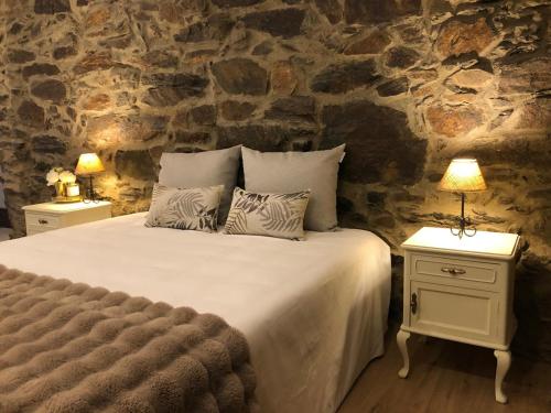 ペーゾ・ダ・レーグアにあるQuinta do Barrocal - Casa de Campoのベッドルーム1室(ランプ2つ、石壁付)