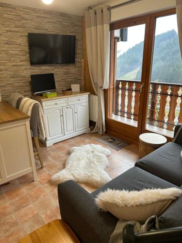 a living room with a couch and a tv at 2-bed appt 20 mins from Morzine Portes du Soleil French Alps in La Baume