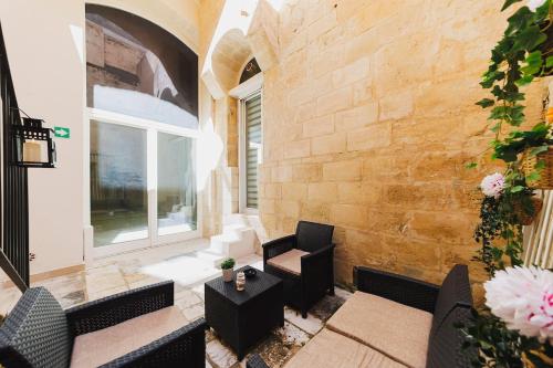 a patio with black furniture and a brick wall at Dimora Castelvecchio-Sassi Di Matera in Matera