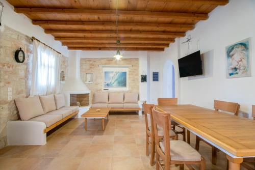 a living room with a wooden table and a couch at Blue Xenia Villas Paros in Chrissi Akti