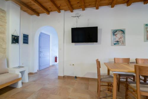 a dining room with a table and a tv on a wall at Blue Xenia Villas Paros in Chrissi Akti