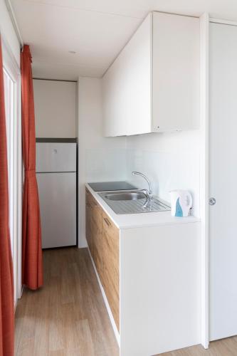 a kitchen with white cabinets and a sink at Camping Rose in Dormelletto