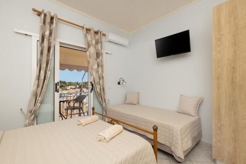 a bedroom with two beds and a balcony at Nafsika Apartments and Studios - Fiskardo in Fiskardho