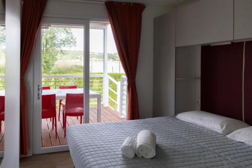 a bedroom with a bed and a balcony with a table at Camping Rose in Dormelletto