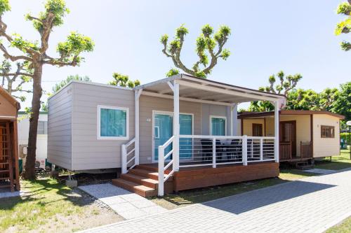 a tiny house with a porch and a deck at Camping Rose in Dormelletto