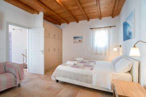a bedroom with a bed and a table and a chair at Blue Xenia Villas Paros in Chrissi Akti