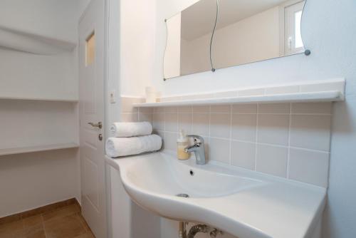 a white bathroom with a sink and a mirror at Blue Xenia Villas Paros in Chrissi Akti