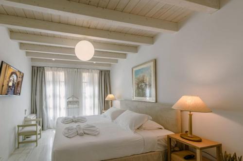 a bedroom with a large white bed with a lamp at Rimondi Residences Rethymno in Rethymno Town