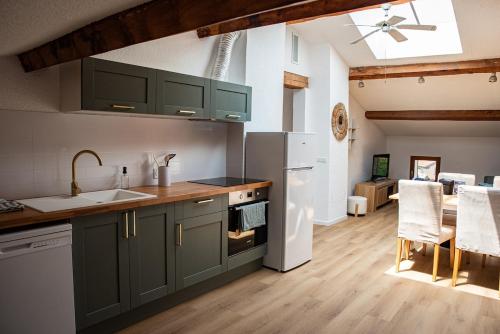 une cuisine avec des placards verts et un salon dans l'établissement Refuge sous les toits, à Perpignan