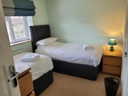 a room with two beds and a table with a lamp at The Holbein Three bedroom home near tilgate park private parking and garden in Crawley