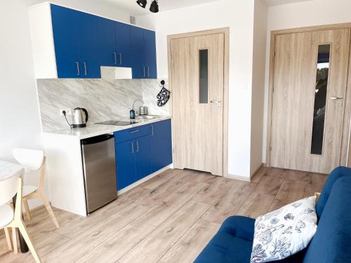 a kitchen with blue cabinets and a blue couch at Apartamenty Magellan LUX 50 m Od Plaży z Dużym Balkonem in Rowy