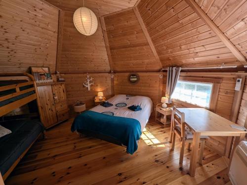 - une chambre dans une cabane en rondins avec un lit et une table dans l'établissement Gîtes en bord de Saône avec hébergements insolites climatisés - FR-1-583-393, à Mantoche