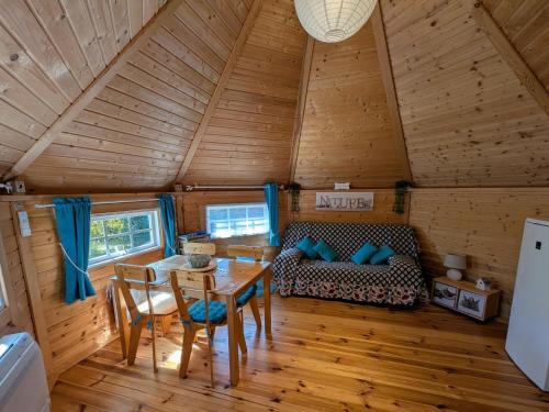 - une salle à manger et un salon dans une cabane en rondins dans l'établissement Gîtes en bord de Saône avec hébergements insolites climatisés - FR-1-583-393, à Mantoche