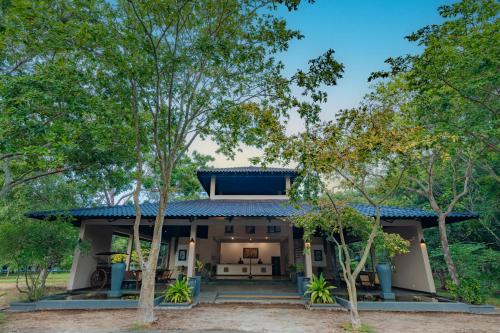 a house with a blue roof and trees at Kassapa Lions Rock in Sigiriya