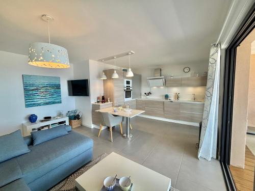 un salon avec un canapé bleu et une table dans l'établissement Appartement 26 les terrasses de l'isolella Porticcio, à Porticcio