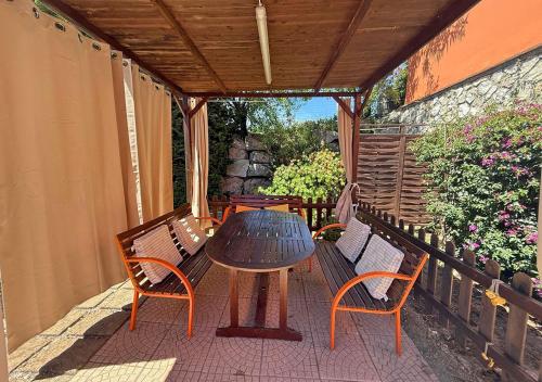 a table and chairs on a patio with a wooden roof at Casa Katia, Giuliana & Nami in Lacona