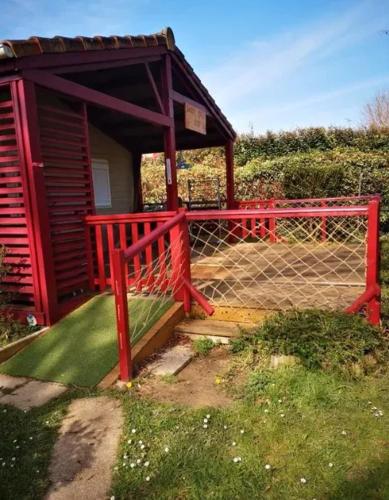 Una pequeña casa roja con una valla y una puerta. en Chalet accueillant avec vue sur le lac, en Estang