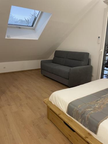 a bedroom with a bed and a couch in a attic at Gîte Belle Vue 2 in Saint-Léger-les-Mélèzes