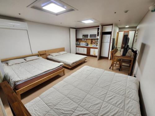 a bedroom with two beds and a kitchen with a desk at Hongdae Sky apartment in Seoul