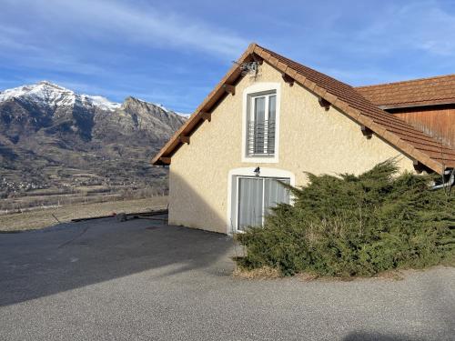 a house with a garage and mountains in the background at Gîte Belle Vue 2 in Saint-Léger-les-Mélèzes