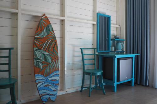 a surfboard leaned up against a wall with a table and chairs at Mahaon surf hotel in Weligama