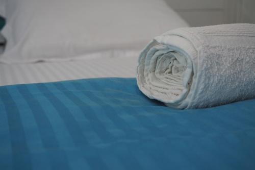 a roll of white towels sitting on a bed at Mahaon surf hotel in Weligama