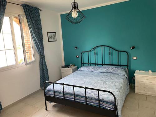 Un dormitorio con una cama y una pared azul. en Villa Magnolia del Mare, en Arenella