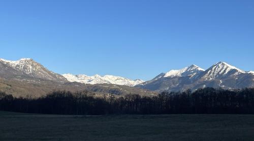 a snow covered mountain range with a field and trees at Gîte Belle Vue 2 in Saint-Léger-les-Mélèzes