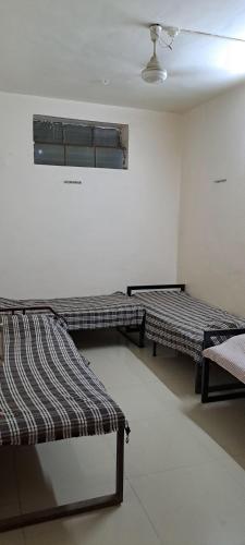 a room with two beds and a window at Hotel Poonam Lodge in Ahmadnagar