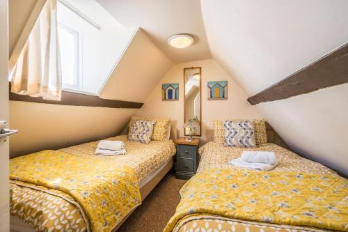 a attic bedroom with two beds and a window at Bovis Cottage, Southwold in Southwold
