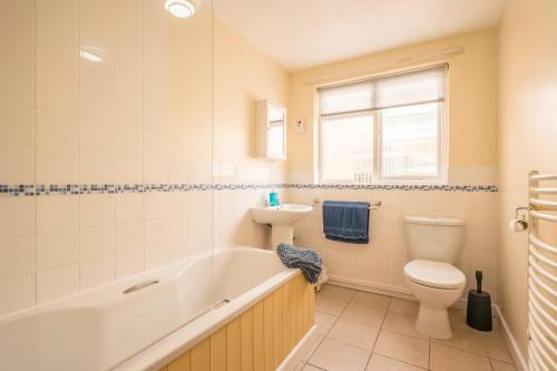 a bathroom with a tub and a toilet and a sink at Bovis Cottage, Southwold in Southwold