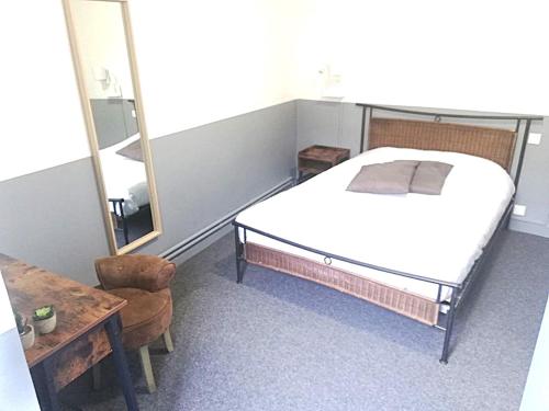 a bedroom with a bed and a mirror and a chair at hôtel BEAUTOUR in Vertou