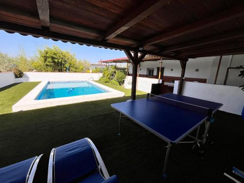 a ping pong table on a patio with a swimming pool at Cortijo Candela in Granada