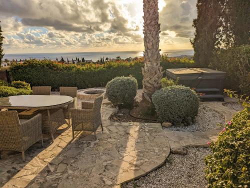 a patio with a table and chairs and a palm tree at Villa Pontus - stunning views & privacy in beautiful garden with pool & hot tub in Kouklia