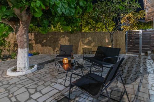 three chairs and a table next to a tree at Beachside Apartment-1 in Afantou