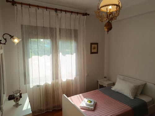 a bedroom with a bed and a chandelier and a window at Cozy Garden House in Árgos Orestikón
