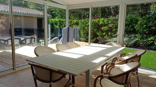- une table et des chaises sur une terrasse avec portes coulissantes en verre dans l'établissement Un écrin de calme envoutant !, à Andernos-les-Bains