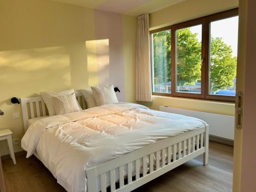 a white bed in a room with a window at Villa Couleur in Diksmuide