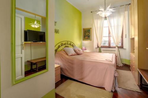 1 dormitorio con 1 cama con sábanas rosas y espejo en Colorful Tuscan Retreat Steps from Casole City Center, en Casole dʼElsa